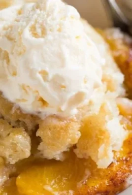 Slice of old fashioned peach cobbler with golden crust and fresh peaches